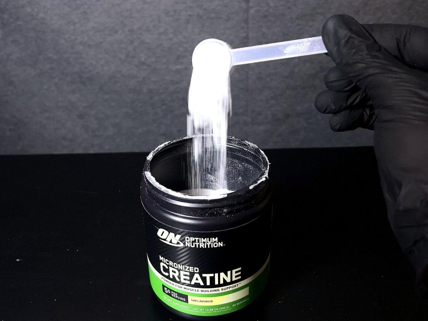 Polvo de creatina micronizada cayendo del scoop al tarro